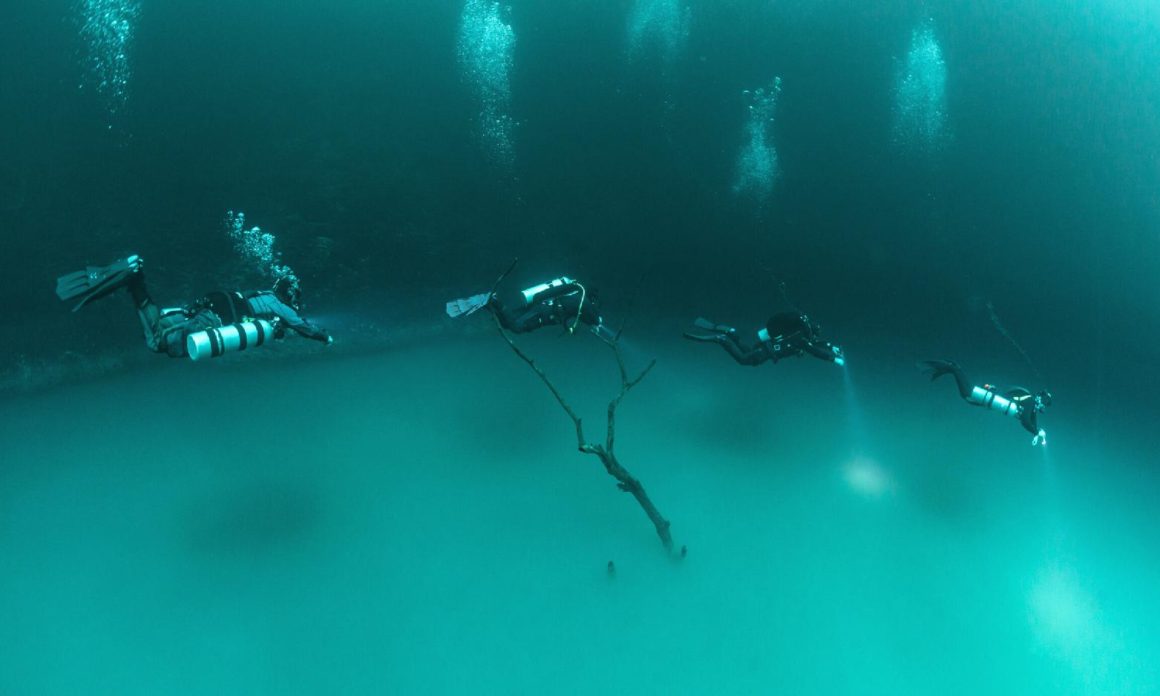 divers swimming in halocline in cenotes near cancun mexico